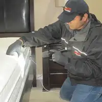 Bed bug inspection technician checking a mattress and bed frame for signs of infestation in Anaheim, CA