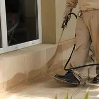 General pest control technician spraying exterior perimeter around a home in Anaheim, CA