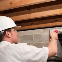 Termite inspection technician checking a basement wall and framing for termite activity in Anaheim, CA