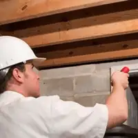 Termite inspection technician checking a basement wall and framing for termite activity in Anaheim, CA